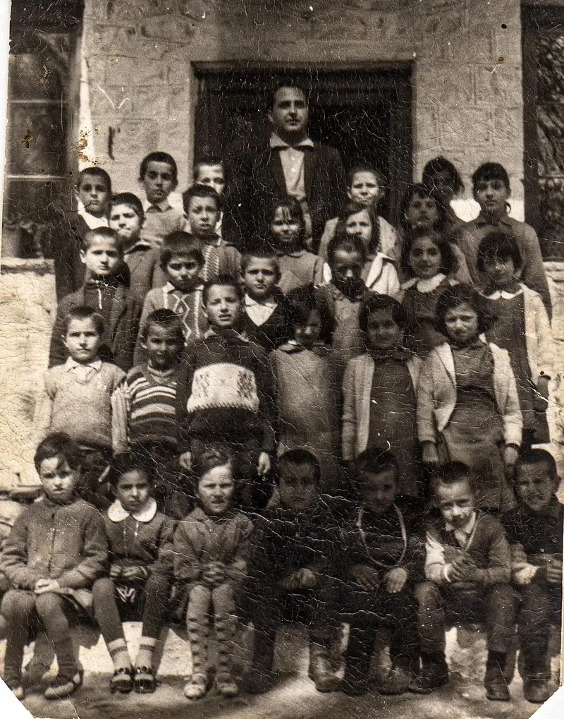 Τάξη παιδιών μπροστά από την πόρτα του σχολείου, με τον δάσκαλο στο βάθος