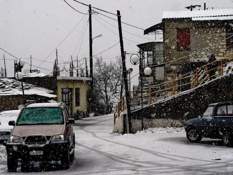 Χιονισμένος δρόμος του χωριού με σταθμευμένα αυτοκίνητα