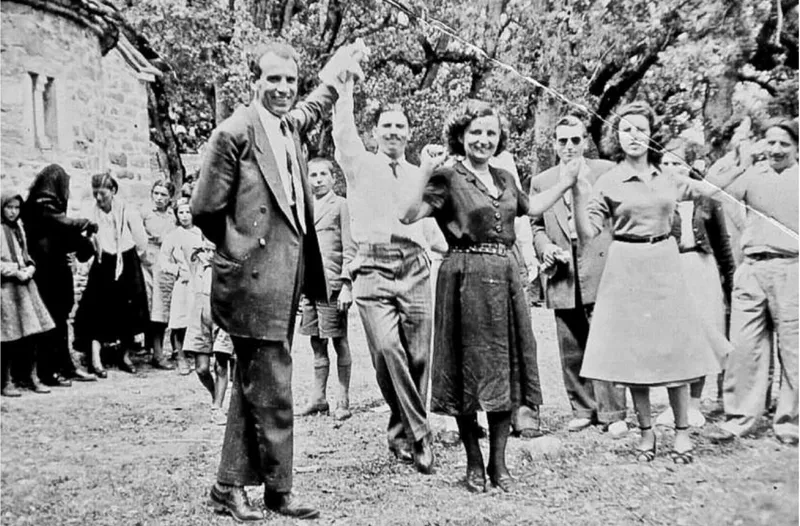 Συγχωριανοί σε υπαίθριο γλέντι, με έναν άνδρα να σηκώνει το χέρι