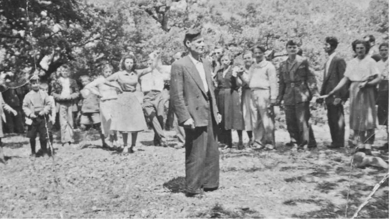 Άνδρας μιλά μπροστά σε ομάδα χωριανών κάτω από τα δέντρα