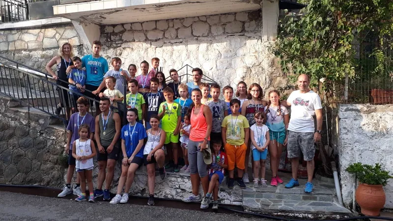 Παιδιά και μεγάλοι με μετάλλια στο λαιμό, ομαδική φωτογραφία στα σκαλιά του χωριού μετά τους αγώνες