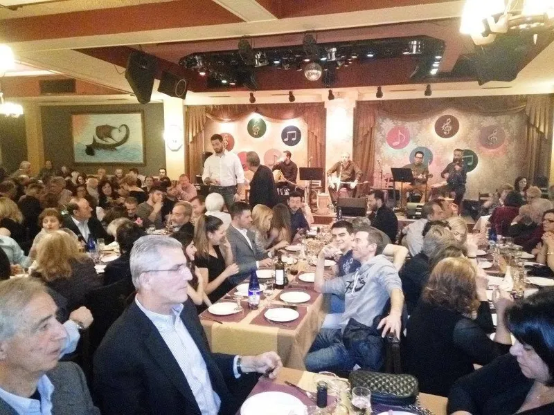 Η αίθουσα γεμάτη με συγχωριανούς στα τραπέζια της εκδήλωσης, με ζωντανή μουσική στη σκηνή
